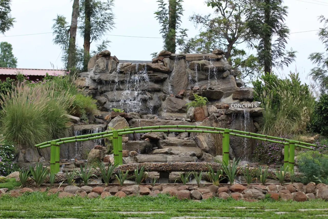 Rock waterfall water feature with bamboo bridge built at Palm Era Resorts