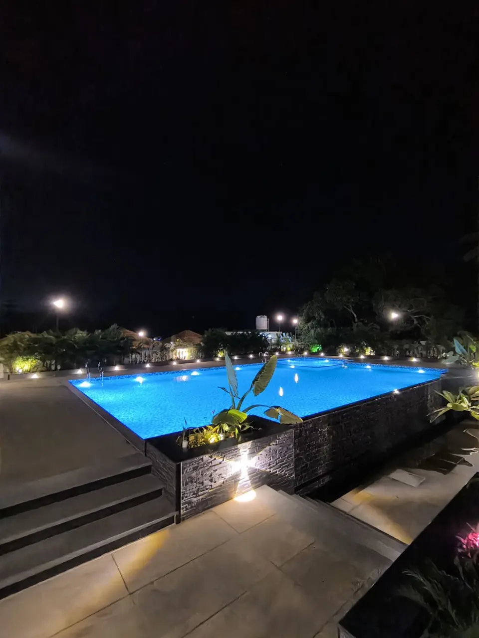 Floodlit swimming pool with stone-clad deck and landscaped grounds, built by CONCEPTS